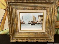 Full view of framed painting showing landscape harbor scene with sailboats and ornate gilded frame.
