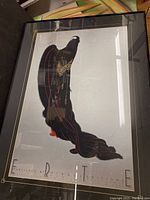 Full view of framed stylized black peacock poster with red and gold accents.