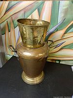 Front view of the large copper and brass vase showing the full shape and flared brass top.