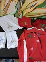 Photo of white towels embroidered with blue Christmas tree and gold Eiffel Tower designs, and red Christmas cloth items.