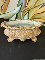 Full view of the painted cast iron jardiniere planter showing its shape, feet, and leaf-like embossed details.