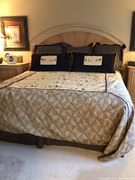 Front view of made king bed with wood headboard, bedding and pillows