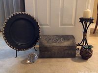 Wide view showing all decorative items: plate on stand, decorated box, candle holder with candle, small plant, and glass sphere