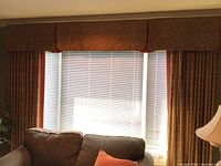 Overall view of the two window drapery panels and the valance above, showing pattern, color, and setting with blinds behind.