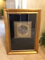 Full view of the framed artwork showing the gold frame and the centered circle design.