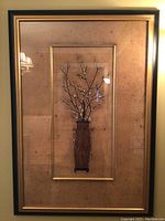 Full view of framed art showing vase with blossoming branches inside dark wood and gold accented frame