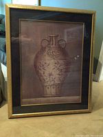 Full view of framed art print showing the ornate vase with floral and decorative patterns. Frame appears gold with a black matte border.