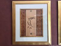 Front view of framed art showing a minimalist face drawing on wood panel with golden frame and glass cover.