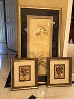 All three framed botanical art prints together, showing the size difference with one larger orchid print and two smaller leafy plant prints.
