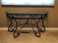 Front view of the demi lune glass top hall table showing curved wrought metal legs and decorative metal frame beneath glass.