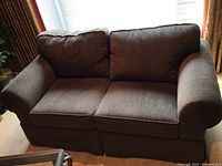 Front view of brown fabric love seat showing two seat cushions and two back cushions with rolled armrests on each side.