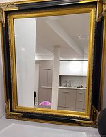 Front view of the large rectangular mirror showing the ornate black and gold frame and reflective surface.