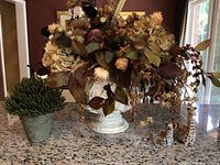 Wide view of floral arrangement with animal figurines and faux potted plant on granite countertop