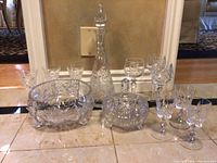 Full view of entire set showing decanter, covered dish, large bowl, and multiple glasses arranged on floor.