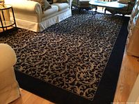 Full view of large rectangular rug on hardwood floor with sofas around, showing the full size and pattern.