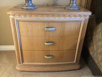 Front view of the three-drawer wooden side table showing the design and metal handles