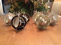 Six vintage tea cups and saucers displayed on wood table with floral arrangement in background.