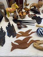 Overview of multiple assorted wooden carved animals and decorative items on a fabric surface.