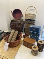 Front view of entire lot arranged on table including woven storage boxes, open baskets with placemats, decorative blue boxes, wooden box, and bark-like containers.