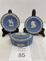 Two small Wedgwood Jasperware plates displayed on stands featuring relief motifs of a Canadian Mountie and Winston Churchill with a round lidded trinket box in front