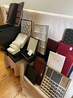 Overview of multiple ring display boxes and inserts arranged on a beige fabric surface, showing variety in sizes and colors.