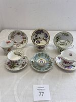 All six matched pairs of vintage English bone china teacup sets with various floral and emblem designs, displayed on white surface.