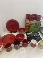 Full view of red speckled enamelware pieces including plates, bowls, mugs, cutlery roll, and Coleman box