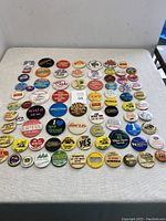 Full display of 82 assorted souvenir and advertising buttons laid out on a table, showing a variety of colorful designs, mostly round and pin-back.