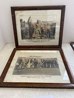 Two framed vintage black and white wrestling photographs leaning against a wall on a white surface.