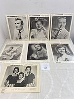 Seven vintage black and white country music publicity photos laid out on a flat white surface with a small card labeled 61