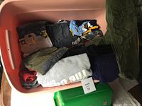 Storage bin filled with folded boy's clothing items in various colors and styles, sizes small and medium.