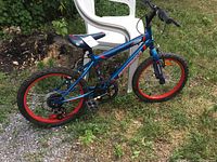 Side view of blue child's bike with red rims and 16-inch tires