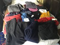 Various children's clothing items laid out on a bed including fleece jackets, sweatshirts, shirts, and pants in boys medium and girls large sizes.