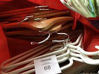 Close up of natural wood and white plastic coat hangers stacked inside red bag