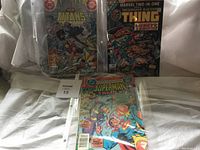Three vintage comic books - New Teen Titans Annual, Marvel Two-in-One featuring Thing, Superman Family - in plastic sleeves