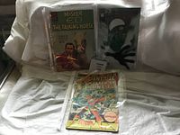 Three comic books including Mister Ed, The Amazing Spider-Man, and Master of Kung Fu, displayed upright and overlapping on a white sheet.