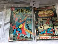 Photo showing two comic books: The New Adventures of Superboy and Superman Family featuring colorful vintage DC Comics covers.