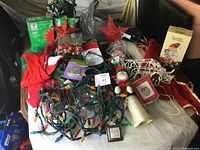 Photo of large lot including red star tree toppers, string lights, Santa and angel figurines, wireframe reindeer, Christmas ball ornaments, and other assorted Christmas decorations in new and used condition.