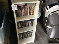 White wooden shelf with DVDs arranged on three shelves