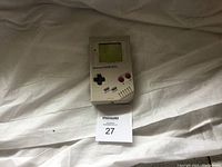 Original Nintendo Game Boy front view on white sheet, showing screen and controls.