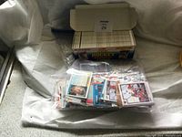 Photo showing a large quantity of loose hockey cards in plastic bags with an Original Hockey box in back.