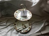 Two-tier ceramic serving stand with matching server utensil, showing overall setup and decorative detail.