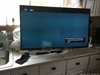 Sony 46-inch flat screen TV powered on showing HDMI 1 input with no signal message, black remote visible on counter below TV.