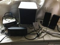 Full set of speakers and CD player, placed on a surface with visible cords and power plugs