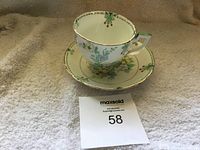 Tea cup on matching saucer with floral pattern and gold rim.