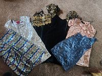 Five different vintage women's dresses laid out showing colors, materials and styles