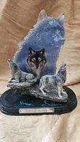 Full view of the wolf figurine sculpture showing three wolves on sculpted terrain and blue wolf head backdrop