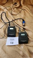 Both Sennheiser body pack units together showing transmitter with blue cable attached and receiver with display.