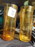 Photo showing both tall amber cylindrical glass vases with visible bubbles in glass.