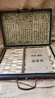 Overview of open Mahjong case showing tiles, dice, and instruction booklet with decorative Chinese text inside lid